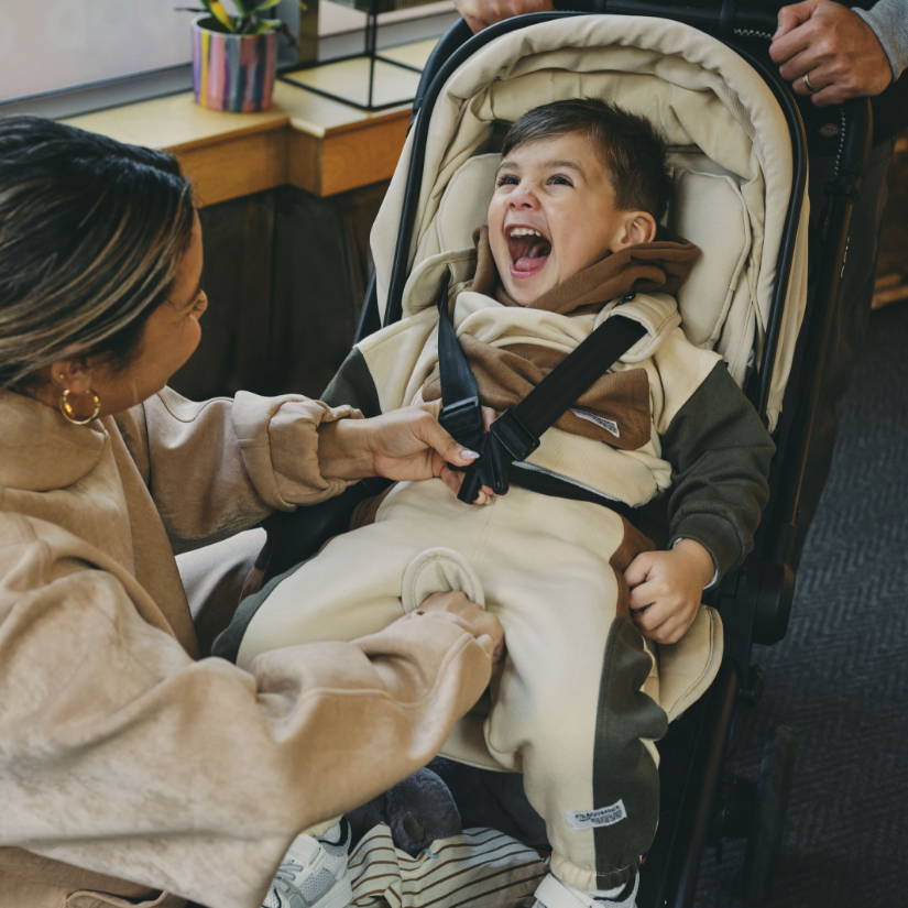 Baby laughing as he is getting strapped into stroller